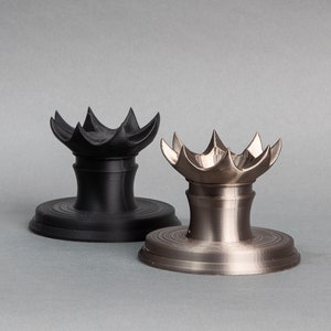 May include: Two decorative stands with a starburst design. One stand is black and the other is silver.