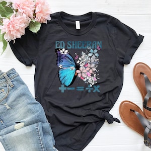 May include: Black t-shirt with a blue butterfly and flowers. The text "Ed Sheeran" and "+=÷x" are printed on the shirt.