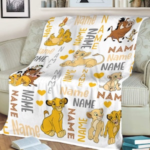 May include: White fleece blanket with a repeating pattern of lion cubs, a warthog, and hearts. The blanket has the word "Name" repeated throughout the design.