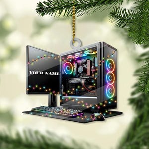 May include: A Christmas ornament shaped like a computer with colorful lights. The ornament has a monitor, a keyboard, and a tower with a clear side panel revealing colorful lights and components. The ornament says "YOUR NAME" on the monitor.