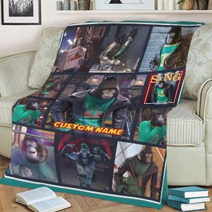 May include: A plush blanket featuring a collage of images from the animated movie "Sing." The design includes various scenes of a gorilla character wearing a green shirt and a black jacket. The blanket has a teal border and the text "CUSTOM NAME".