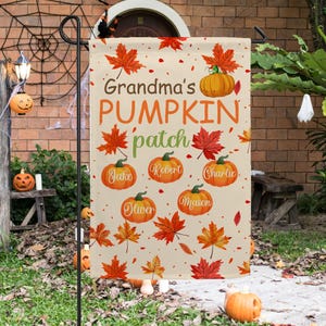 Könnte beinhalten: Eine beige Gartenflagge mit dem Text "Grandma's PUMPKIN patch" und den Namen Jake, Robert, Charlie, Oliver und Mason auf Kürbissen. Die Flagge ist mit orangefarbenen und roten Ahornblättern und Kürbissen verziert.