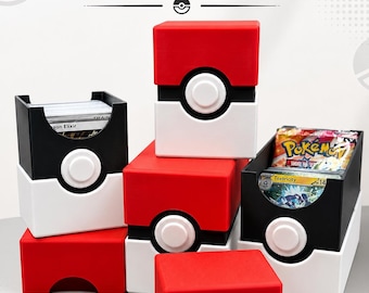 Puede incluir: Una colección de cajas de almacenamiento apilables para juegos de cartas coleccionables, diseñadas como Poké Balls rojas, blancas y negras. Las cajas cuentan con un botón circular central, algunas abiertas mostrando mazos y paquetes de cartas.