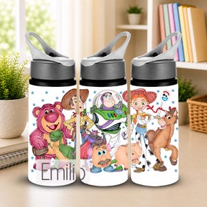 May include: A white water bottle with a grey lid and handle, featuring a colourful graphic print of various animated characters including a pink bear, a cowboy, a space ranger, a cowgirl, a horse, and a spork, with the name Emilio printed.