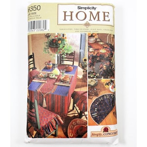 Op de afbeelding: Simplicity Home naaipatroon voor tafelkleden, tafelrunners, placemats, stoelhoezen en bestekmand. Het patroon toont verschillende ontwerpen met een zuidwestelijk thema, waaronder een rood-blauw-wit gestreept tafelkleed met kwastjes, een bloemig tafelkleed en een blauw-wit placemat met een gegolfde rand.