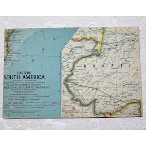 Puede incluir: Un mapa vintage de América del Sur oriental, específicamente Brasil, con un fondo azul claro y líneas marrones que representan ríos y fronteras. El mapa se titula "Eastern South America" e incluye el texto "Atlas Plate 27 September 1962" y "Compiled and Drawn in the Cartographic Division of the National Geographic Society for NATIONAL GEOGRAPHIC MAGAZINE".