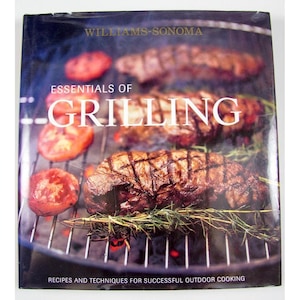 May include: A cookbook titled "Essentials of Grilling" by Williams-Sonoma. The cover features grilled steaks and tomatoes on a grill. The book's title is in large white letters, with the subtitle "Recipes and Techniques for Successful Outdoor Cooking."