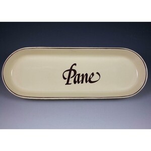 Peut inclure: Plat à pain ovale de couleur crème avec une bordure marron foncé et le mot "Pane" en écriture élégante. Un plat simple mais élégant pour servir du pain ou d'autres aliments.