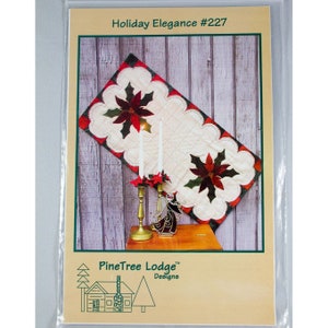 May include: A quilting pattern for a table runner featuring a poinsettia design with red, green, and white colors. The pattern is titled "Holiday Elegance #227" and is from PineTree Lodge Designs.