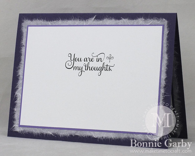 May include: A purple card with a white border and a white fluffy edge. The card has the text "You are in my thoughts." written in black cursive.