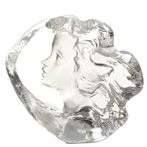 May include: A clear glass sculpture of a woman's face with flowing hair. The sculpture is abstract and modern in style.