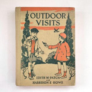 Op de afbeelding: Een vintage boekomslag met een oranje en zwarte illustratie van twee kinderen in een bosrijke omgeving. De titel van het boek is "OUTDOOR VISITS" door Edith M. Patch en Harrison E. Howe.