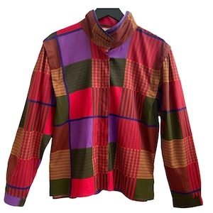 May include: A long-sleeved button-up shirt with a checkered pattern in shades of red, purple, brown, and green.