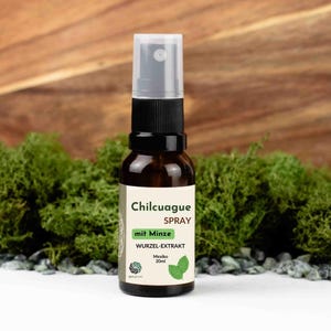 Puede incluir: Una botella de spray de vidrio marrón con tapa negra y etiqueta blanca. La etiqueta dice "Chilcuague Spray" con el texto "mit Minze" y "Wurzel-Extrakt". La botella contiene 20 ml de producto y está sobre un fondo de musgo verde y madera.