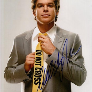 May include: A portrait of a man in a gray suit, white shirt, and yellow tie. The tie has the words "DO NOT CROSS" printed on it. The image is signed in blue ink.