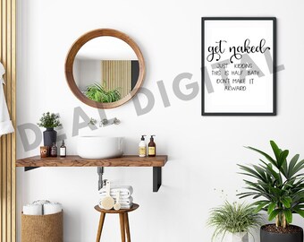 May include: A rectangular wall art print in a black frame featuring the black text: get naked JUST KIDDING THIS IS HALF BATH DON'T MAKE IT AKWARD. The print is displayed in a bathroom with a round wooden mirror, a white vessel sink, and plants.