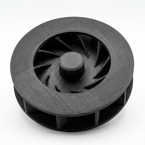 Peut inclure: Une roue à aubes circulaire noire dotée d'un moyeu central et d'une série de pales internes incurvées. L'objet présente une finition de surface texturée cohérente avec la fabrication additive, avec des lignes de couche visibles.