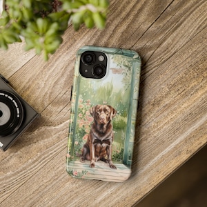 Puede incluir: Una funda para teléfono con una ilustración de acuarela de un labrador retriever marrón chocolate sentado en un porche con una puerta verde y flores rosas. La funda del teléfono tiene un recorte para el objetivo de la cámara.