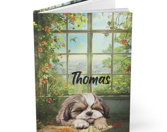 May include: A hardcover journal with the name "Thomas" printed on the cover. The cover features a watercolor illustration of a sleeping Shih Tzu dog in front of a window with a scenic view.