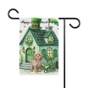 May include: A St. Patrick's Day garden flag featuring a green house with a shamrock door, a green hat, and a brown dog. The flag has the text "Happy St. Patrick's Day" and the name "Charlie". The flag is held by a black metal stand.