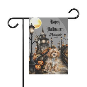 May include: A rectangular garden flag hanging on a black metal stand. The flag features a brown dog sitting on a stone bridge at night, with a full moon, a dark house, street lamps, and orange jack-o'-lanterns. The text reads Happy Halloween Maggie.