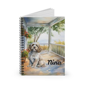 Può includere: Un dipinto ad acquerello di un cane bianco e marrone seduto su un portico con pavimento in legno. Il cane guarda la fotocamera. Il portico ha una ringhiera bianca e una vista su uno specchio d'acqua. Il dipinto è intitolato "Nina".