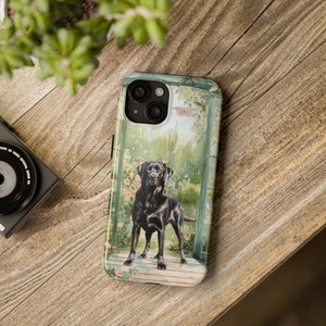 Puede incluir: Un labrador retriever negro se encuentra de pie en una puerta con un diseño floral. La funda del teléfono presenta una pintura de acuarela del perro y la puerta.