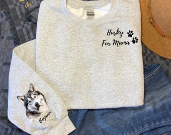 Op de afbeelding: Grijs sweatshirt met de tekst "Husky Fur Mama" en poot afdrukken op de voorkant. De linkermouw heeft een zwart-witte husky hond afbeelding met de naam "Benjamin" eronder.