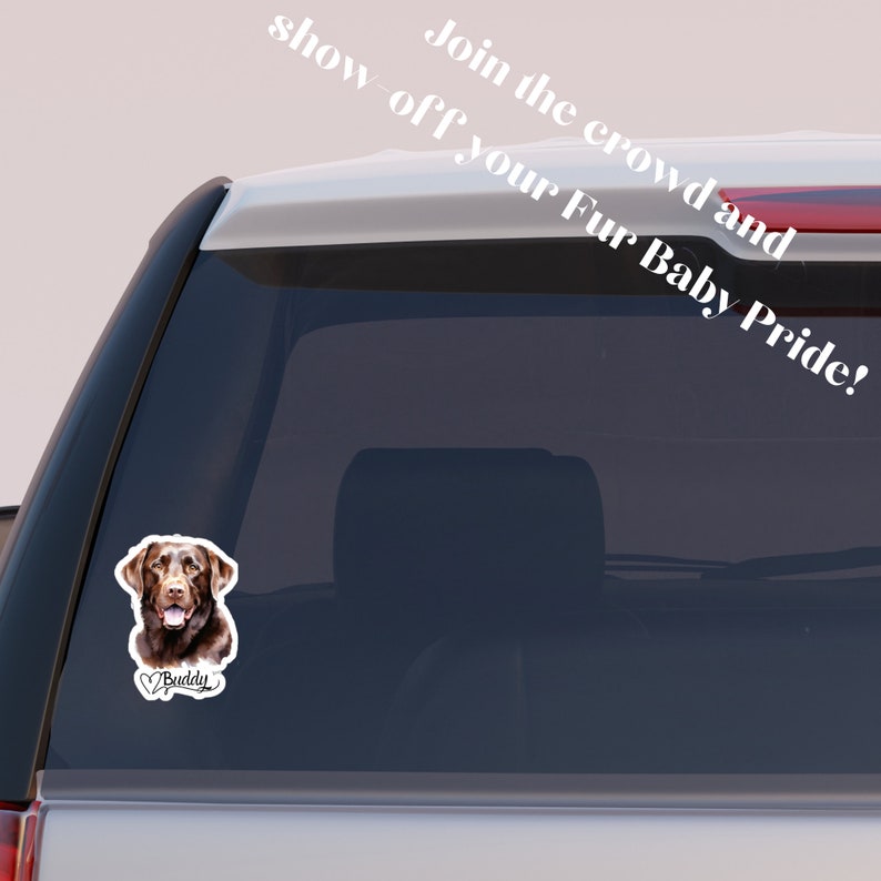 May include: A brown Labrador Retriever dog with a heart and the word "Buddy" underneath. The dog is on a white sticker on the back window of a silver car. The text "Join the crowd and show off your Fur Baby Pride!" is on the window above the sticker.