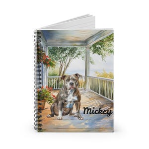 May include: Spiral-bound notebook featuring a watercolor painting of a dog named Mickey sitting on a porch. The dog is brown and white, with a focused expression. The porch has white railings and a view of trees and water.