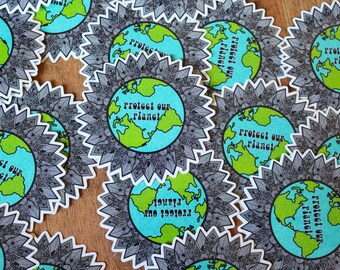 May include: A collection of colourful stickers with a mandala design and the text "Protect our Planet" printed on each sticker. The stickers feature a blue and green globe with continents outlined in green.
