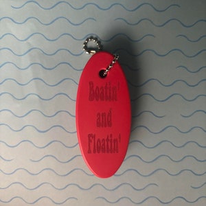 May include: Red oval-shaped keyring with a silver chain. The keyring has the text "Boat'n and Float'n" engraved on it.