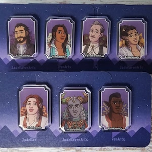 May include: A collection of seven character portrait pins displayed on a dark blue card. Each pin showcases a different character with distinct features and clothing, framed in purple. The pins are arranged on two rectangular cards with a starry sky design.