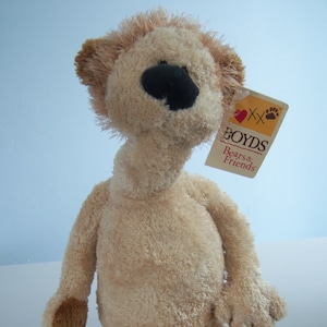 May include: A beige plush toy bear with brown feet and a black nose. The bear has a tag that says "Boyds Bears & Friends" with a red heart and a paw print.
