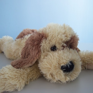May include: A plush brown and cream colored dog toy with a long, fluffy body and brown ears. The toy has a black nose and brown eyes.