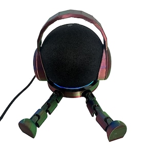 May include: A black spherical speaker is held by a headset-shaped stand and legs, all with an iridescent, colour-shifting finish. The stand and legs are articulated, and a blue light shines from the base.