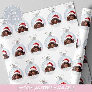 May include: White wrapping paper featuring a repeating pattern of dog faces inside Christmas ornaments, each wearing a Santa hat. The text "LOTS MORE BREEDS AVAILABLE" and "MATCHING ITEMS AVAILABLE" are also visible.