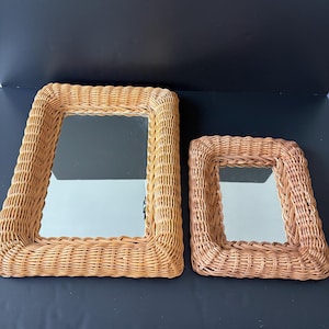 May include: Two rectangular mirrors with light brown woven wicker frames. The larger mirror is positioned on the left, and the smaller mirror is on the right. Both mirrors feature a thick, braided border made of natural rattan material.