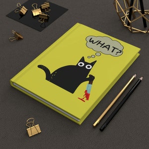 May include: A yellow notebook with a black cat holding a knife and a thought bubble that says "WHAT?"