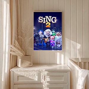 May include: A framed poster for the animated film "Sing 2", showing a group of cartoon animal characters. The poster has a dark blue background with the film's title in white and yellow. The characters include a lion, a pig, and a koala.