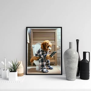 Peut inclure: Une impression encadrée représentant un chien en pyjama à carreaux assis sur des toilettes, regardant un smartphone. Le chien a des poils bruns et se trouve dans une salle de bain. L'impression est sur une surface blanche avec des vases décoratifs.