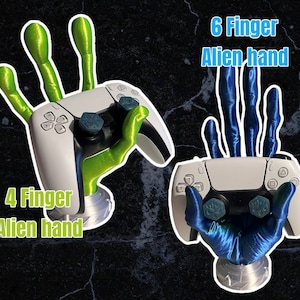 May include: Two 3D printed alien hands holding a white PlayStation 5 controller. The hand on the left has four fingers and is green. The hand on the right has six fingers and is blue. The text "4 Finger Alien hand" is below the left hand and "6 Finger Alien hand" is above the right hand.