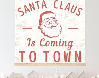 Puede incluir: Un letrero navideño rectangular con el texto "SANTA CLAUS Is Coming TO TOWN" en letras rojas. El letrero presenta una ilustración vintage de Papá Noel. El letrero está colgado con un marco de madera y una cuerda.