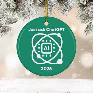 May include: A round green ceramic ornament featuring the white text Just ask ChatGPT at the top, a central white graphic of an atom symbol surrounding a square chip icon labeled AI, and the year 2026 printed in white at the bottom with a gold string.