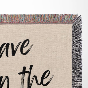 May include: A woven throw blanket with a tan background and black text that reads "Save the" with a fringe border.
