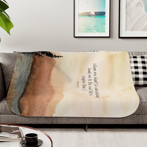 May include: A soft, beige throw blanket with a watercolour landscape design. The blanket features a quote from Psalm 18:2: "When my heart is overwhelmed, lead me to the rock that is higher than I."