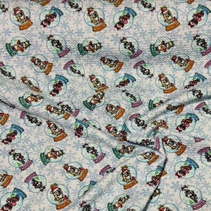 May include: White fabric with a repeating pattern of snow globes. Each snow globe features a cartoon dog wearing a Santa hat and a red scarf. The background is a light blue with a snowflake pattern.
