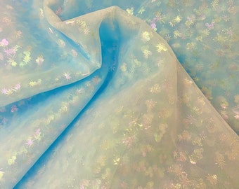 May include: Light blue tulle fabric with iridescent white stars. The fabric is sheer and has a delicate texture.