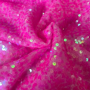 May include: Pink iridescent sequins on a sheer mesh fabric. The sequins are round and have a holographic finish.