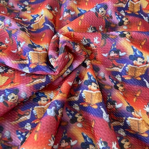 May include: Red and purple fabric with a repeating pattern of Mickey Mouse dressed as a wizard. Mickey is holding a book and a wand. The background is a swirling galaxy pattern.